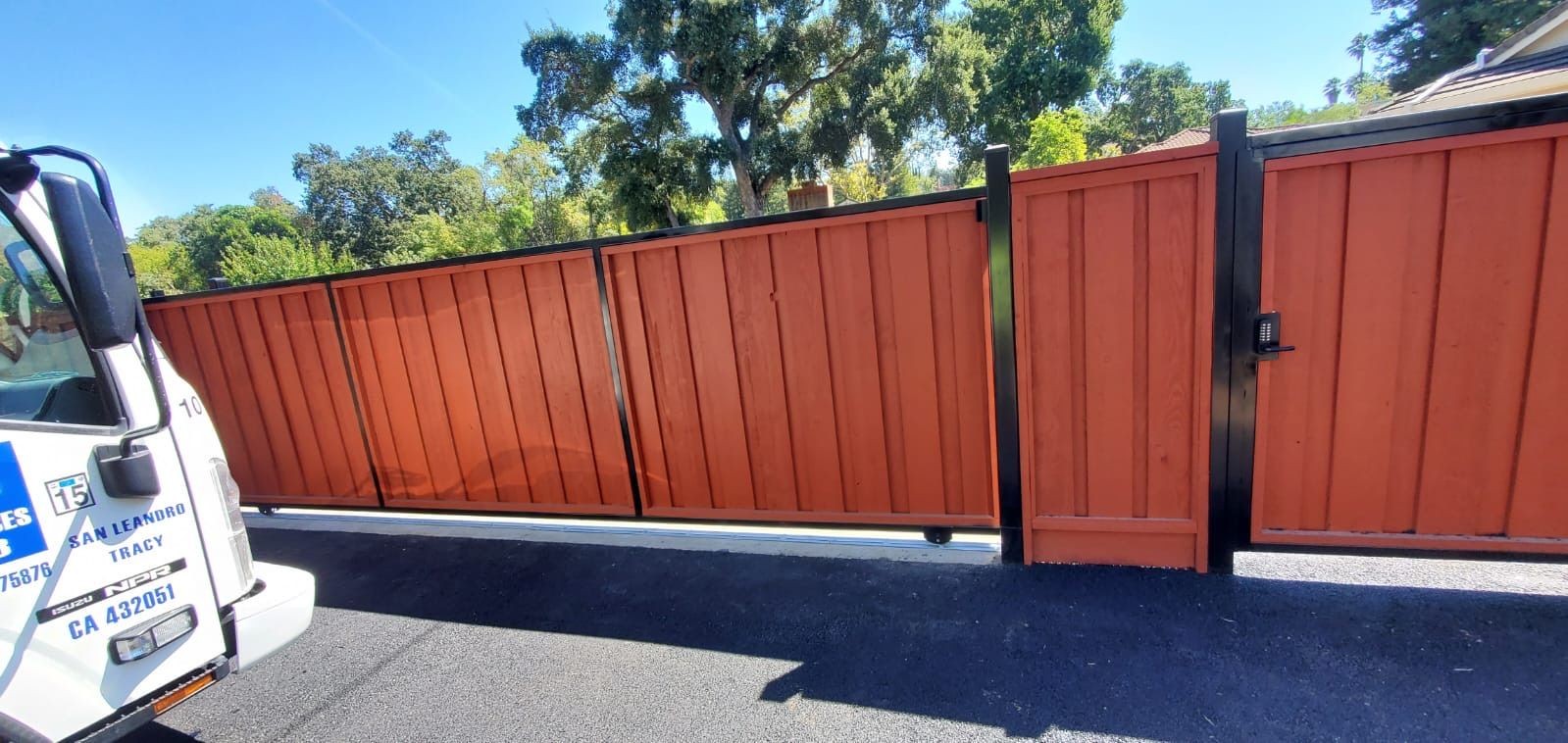 Fabricated driveway gate with welded frame and hinges, installed on commercial lot entrance