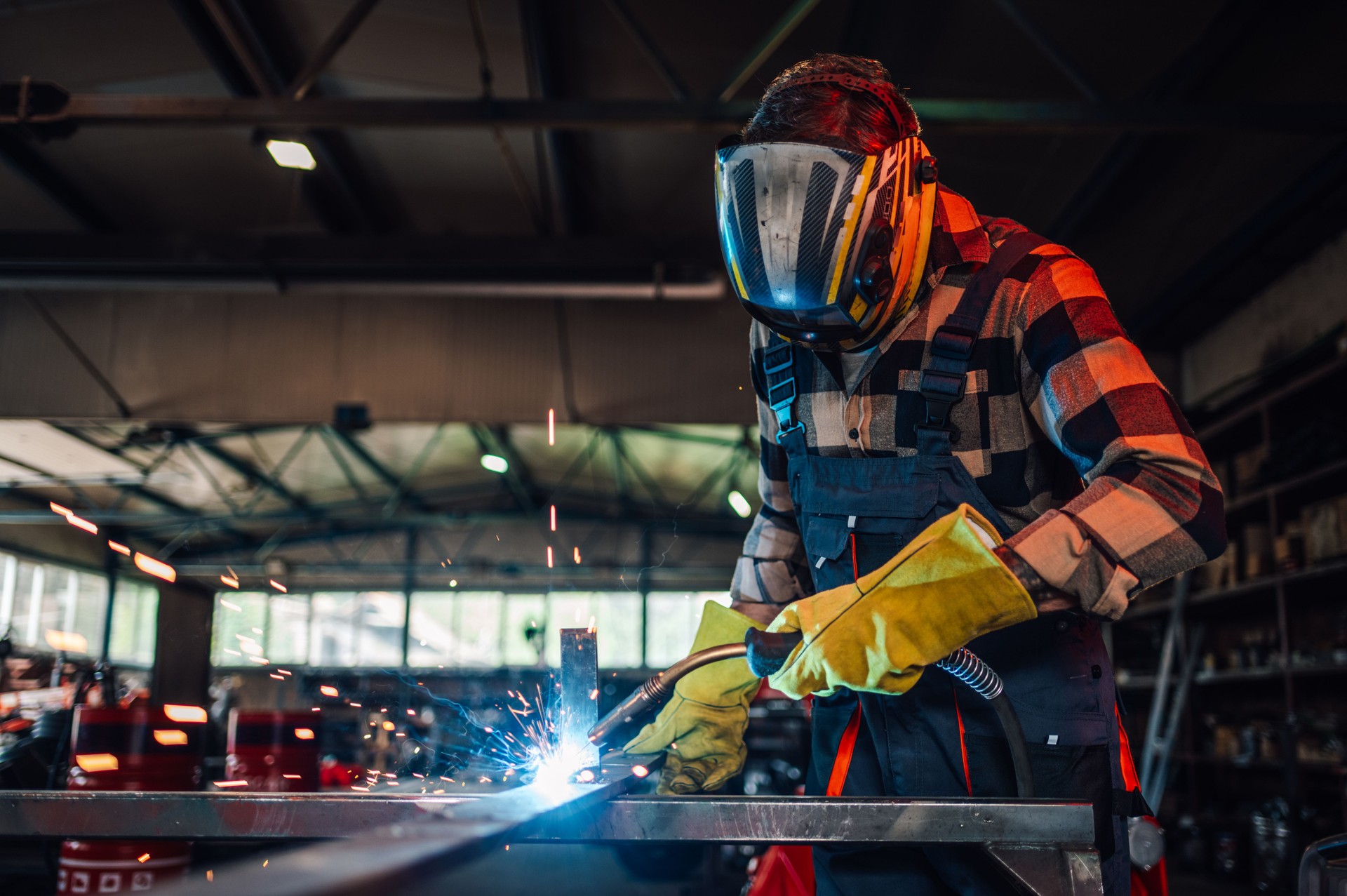 Young man welding a piece of metal while making a metal construction.