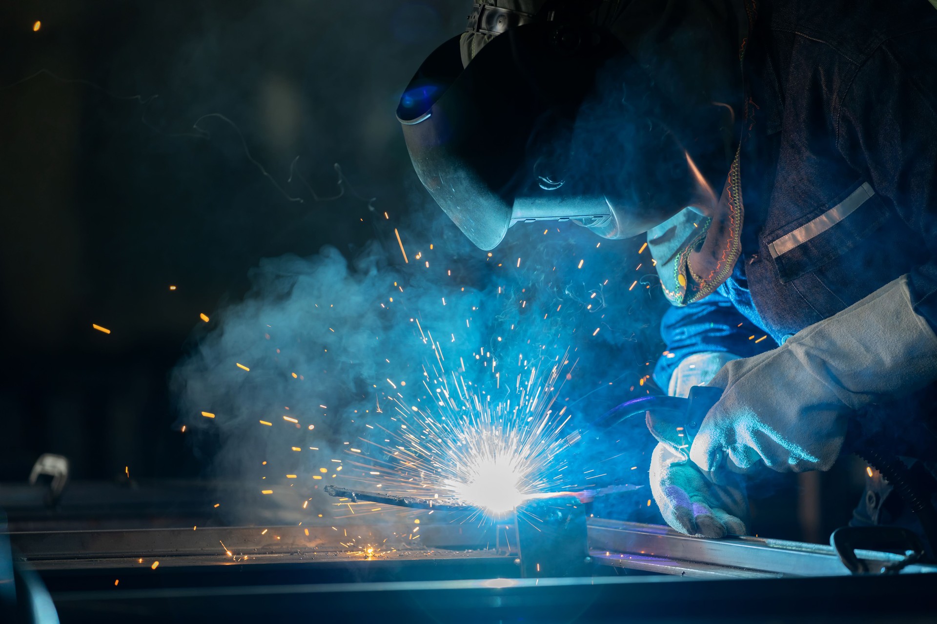 Close-up of our welder performing MIG welding with protective gear in the  metal fabrication shop